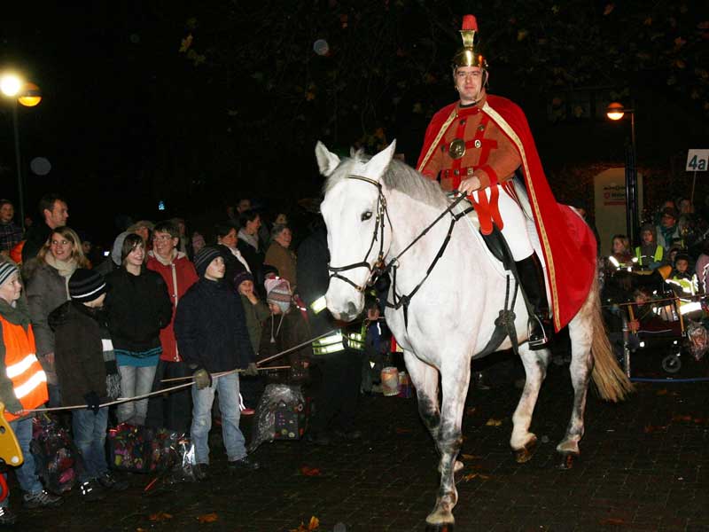 Reiter in Martinskostüm auf weißem Pferd vor Kinder mit Laternen