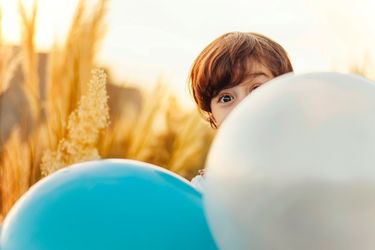 Junge versteckt sich hinter Luftballons