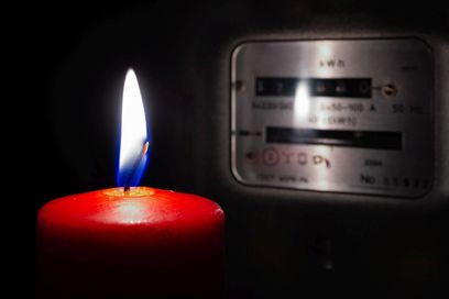 Brennende Kerze vor einem Stromzähler